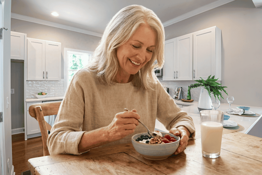 Vital vitamins for women over 50 shown through a vibrant breakfast prepared by a woman in her 50s