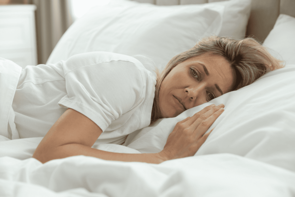 Woman in midlife lying exhausted in bed during the day, illustrating how menopause fatigue can drain energy and disrupt daily life