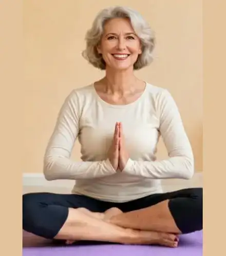 Smiling older woman practicing yoga in a calm space, symbolizing fitness, balance, and wellness for women over 50