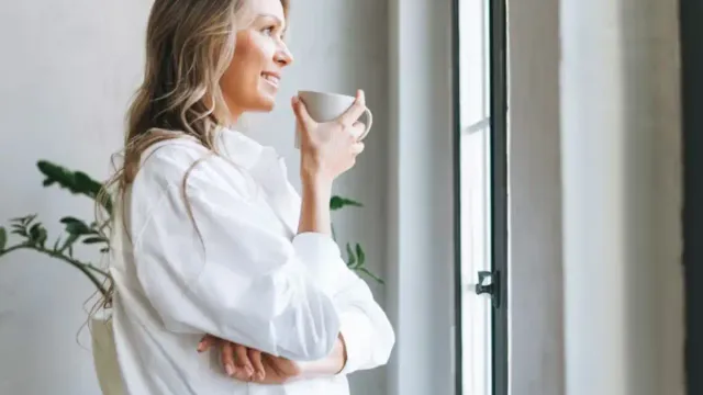 Postmenopause Symptoms:A woman in her 50s enjoying morning coffee, representing postmenopausal daily life and wellness
