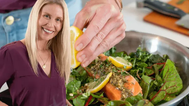 Smiling woman cooking a healthy meal with salmon and greens, highlighting nutritious foods rich in vitamin D and calcium.