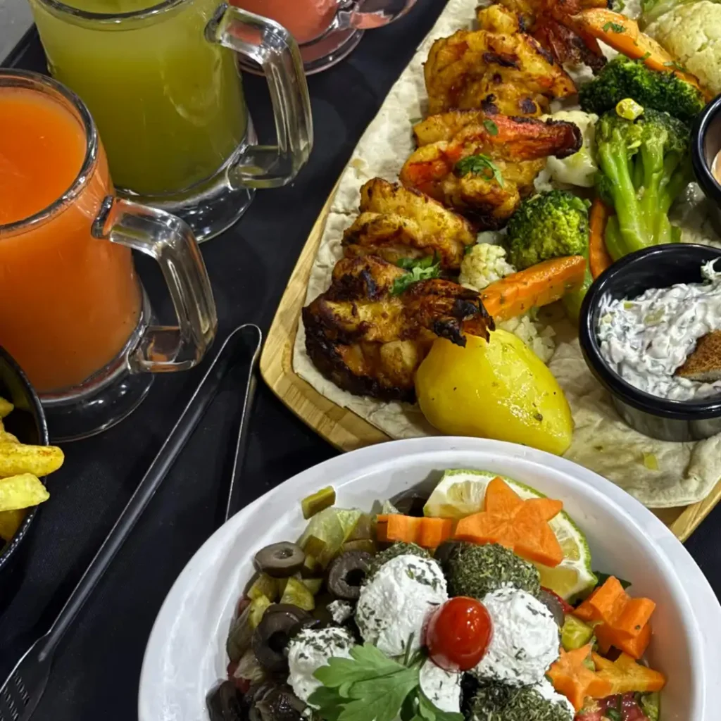 Colorful Mediterranean-style meal with grilled shrimp, mixed vegetables, salad, and fresh juices on a dark table, representing a nutrient-rich diet for healthy aging.