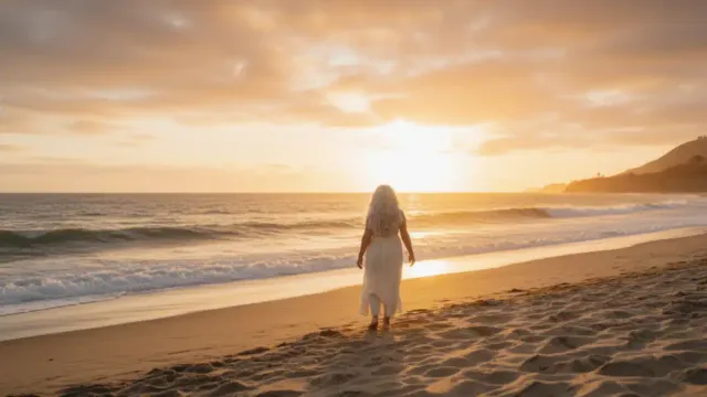 Woman over 50 in transformative moment standing on beach at sunset reflecting on life changes.
