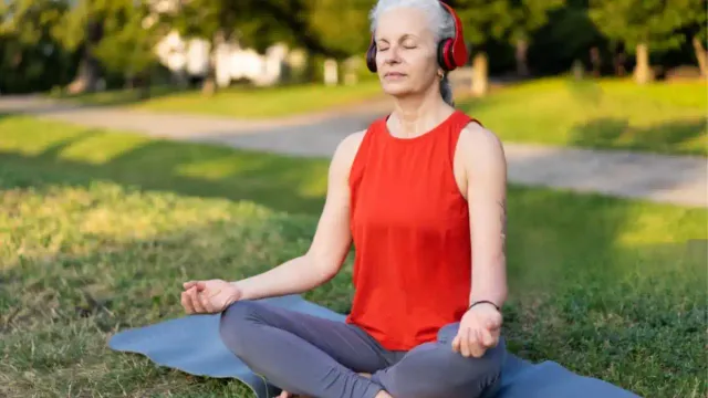Woman over 50 practices seated meditation on a yoga in the soft morning light.