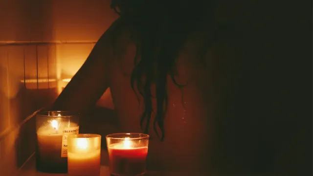Woman in dimly lit bathroom preparing for dark showering evening ritual