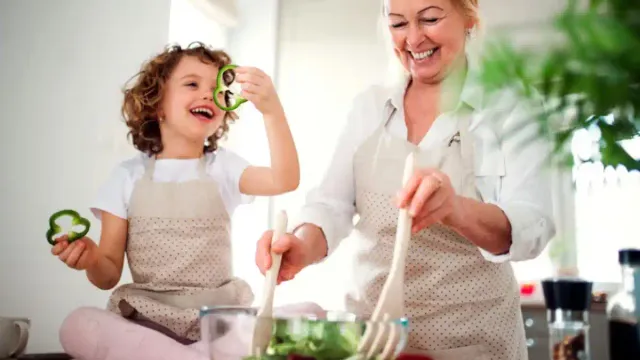 Vibrant grandmother in her 60s playing actively with grandchild, showing typical personality of modern grandmothers