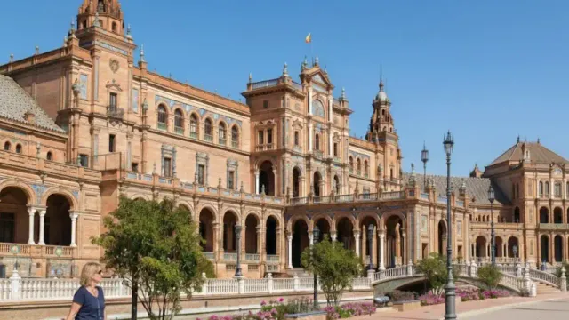 Confident woman in her 50s exploring empty plaza in Seville during off-peak travel season